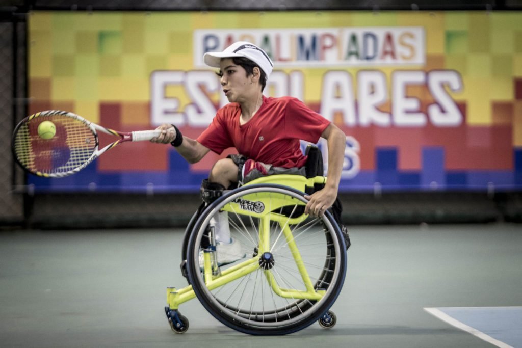 Descrição da imagem #PraCegoVer: Imagem no formato retangular, na horizontal. Nela, o atleta João Lucas Takaki disputa uma competição de tênis em cadeira de rodas durante as Paralimpíadas Escolares. Fim da descrição.