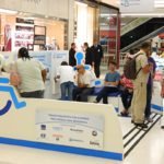 Descrição da imagem #PraCegoVer: A imagem está no formato retangular, na horizontal. Nela é possível ver o estande do Oportunidades Especiais instalado em um corredor de shopping center. Muitas pessoas estão no local, em busca de oportunidades profissionais. Fim da descrição