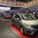 Descrição da imagem #PraCegoVer: O estande de uma montadora de carros com alguns modelos expostos durante a Reatech. Em destaque, um modelo Honda Fit, na cor cinza. Fim da descrição.
