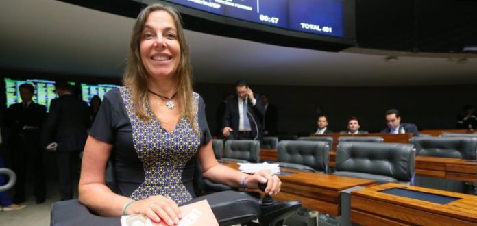 Descrição da imagem #PraCegoVer: Imagem no formato retangular, na horizontal. A deputada Mara Gabrilli está na plenária da câmara dos deputados, em Brasília. Ela está sorrindo. Fim da descrição.