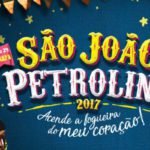 Descrição da imagem #PraCegoVer: Imagem no formato retangular, na horizontal. O cartaz traz as informações sobre o evento São João de Petrolina 2017. Abaixo do nome do evento está uma frase: Acende a fogueira do meu coração! No canto superior da imagem estão ilustrações de algumas bandeirinhas de festa junina. A imagem tem fundo azul. Fim da descrição.