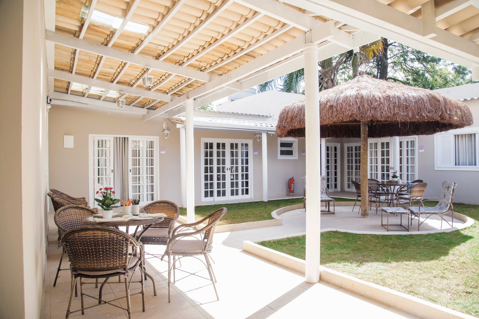 Descrição da imagem #PraCegoVer: A imagem está no formato retangular, na horizontal. Ela mostra o quintal do residencial. É possível ver a varanda de duas residências, em meio a um gramado. Fim da descrição.