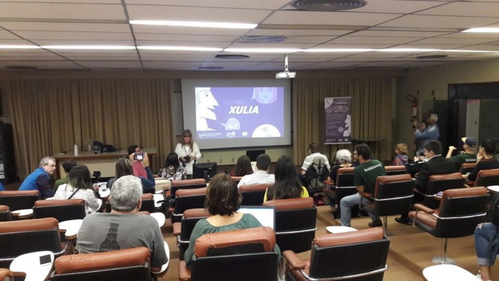 Descrição da imagem #PraCegoVer: Imagem no formato retangular, na horizontal. O auditório na Universidade Federal do Rio de Janeiro, durante o lançamento do software. Na imagem vemos, ao fundo, um telão, onde o software está sendo apresentado. Os presentes ao evento estão sentados nas poltronas do auditório. Fim da descrição.