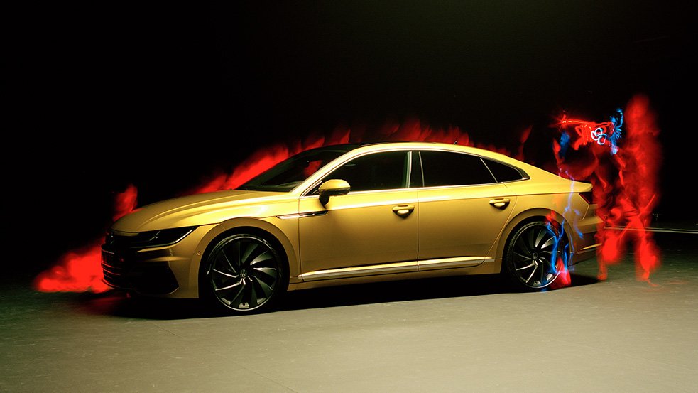 Descrição da imagem #PraCegoVer: Imagem no formato retangular, na horizontal. A imagem tem fundo preto. Nela vemos a lateral do carro. O carro está no centro da imagem. O carro é amarelo e tem à sua volta uma luz vermelha. Fim da descrição.