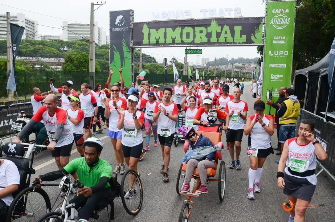 Descrição da imagem #PraCegoVer: Imagem no formato retangular, na horizontal. Um grupo de participantes do projeto Pernas de Aluguel durante uma corrida, que teve a participação de pessoas com deficiência. Entre os corredores, vemos participantes em cadeiras de rodas. Eles acabaram de cruzar a linha de chegada. Fim da descrição.