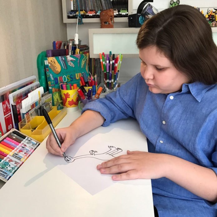 Descrição da imagem #PraCegoVer: O jovem Thor está em sua mesa de trabalho, desenhando uma ilustração para seus livros. Fim da descrição.