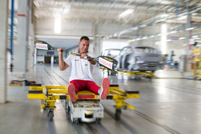 Descrição da imagem #PraCegoVer: Imagem no formato retangular, na horizontal. O paratleta Caio Ribeiro rema sobre um robô no Complexo Industrial da Nissan. Fim da descrição.