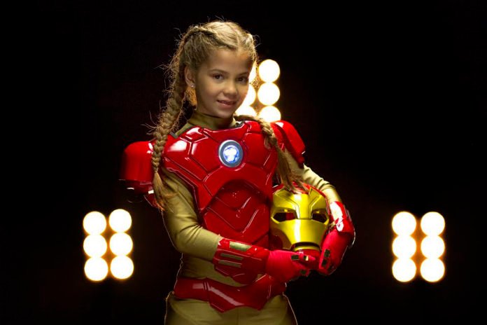 Descrição da imagem #PraCegoVer: Imagem no formato retangular, na horizontal. A menina Letícia, a criança símbolo do Teleton 2017. Ela está vestindo uma fantasia do super-herói Homem de Ferro. Fim da descrição.