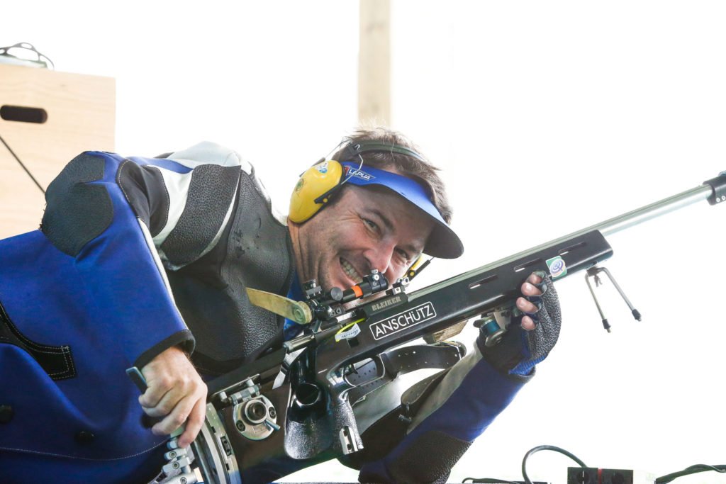 Descrição da imagem #PraCegoVer: Imagem no formato retangular, na horizontal. O paratleta Carlos Garletti, durante torneio de Tiro Esportivo. Ele está deitado e segura uma carabina. Fim da descrição.
