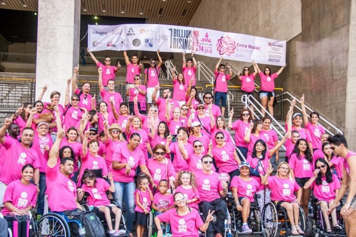 Descrição da imagem #PraCegoVer: Imagem no formato retangular, na horizontal. Voluntários do instituto Entre Rodas durante evento, em São Paulo. Eles estão em uma escadaria, e usam uma camiseta rosa. Fim da descrição.