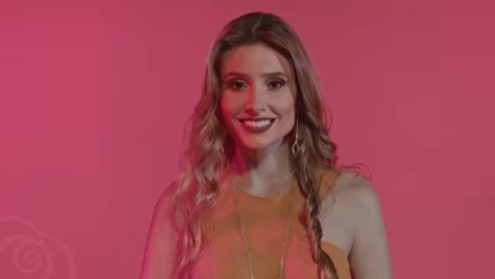 Descrição da imagem #PraCegoVer: Imagem no formato retangular, na horizontal. A modelo surda Thaisy Payo, uma das estrelas da campanha do amaciante Downy. Thaisy está de close. Ela é uma mulher com pele clara, cabelos loiros compridos, e usa vestido laranja. Ela está sorrindo. Fim da descrição.
