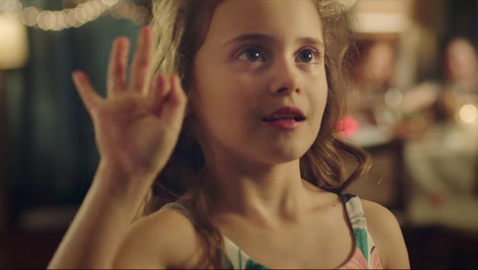 Descrição da imagem #PraCegoVer: Imagem no formato retangular, na horizontal. Imagem da campanha de Natal. Uma menina de pele e cabelos claros, está fazendo um sinal em Libras. Fim da descrição.