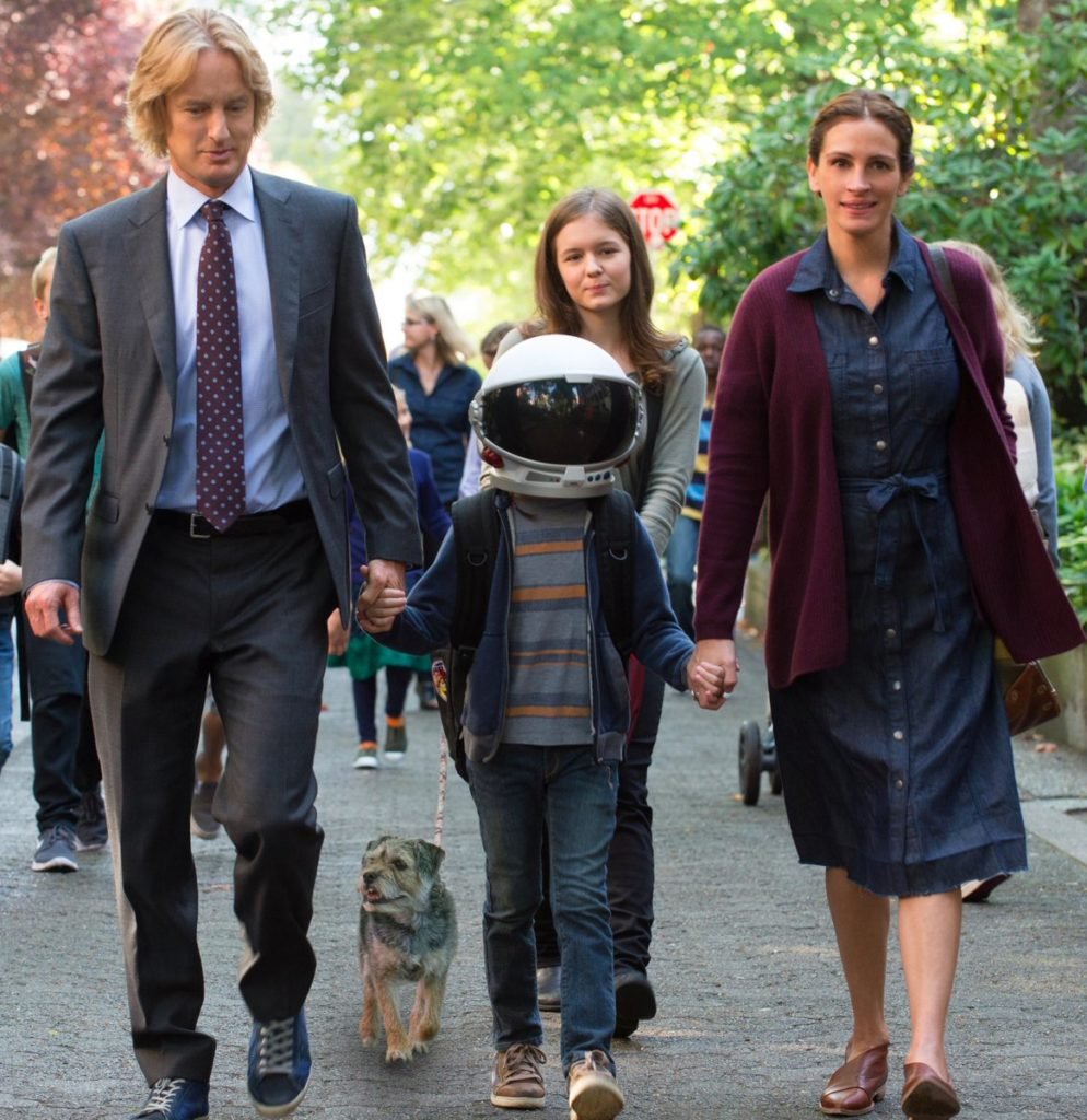 Descrição da imagem #PraCegoVer: Imagem no formato quadrado. Cena do filme Extraordinário. Nela Owen Wilson e Julia Roberts levam o filho para a escola pela primeira vez. O menino, que tem uma malformação facial, está usando um capacete branco para esconder o rosto. Fim da descrição.