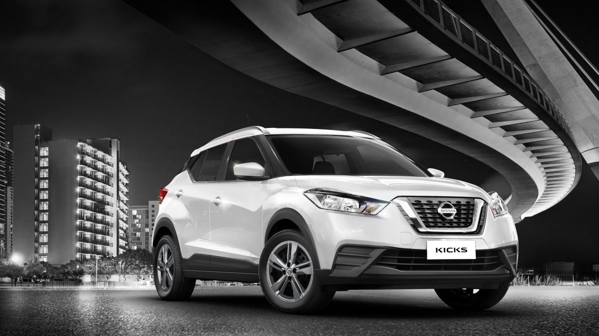 Descrição da Imagem #PraTodosVerem: Imagem no formato retangular, na horizontal. Imagem do Nissan Kicks branco. Ele está em rua rua, em baixo de um viaduto. Fim da descrição.