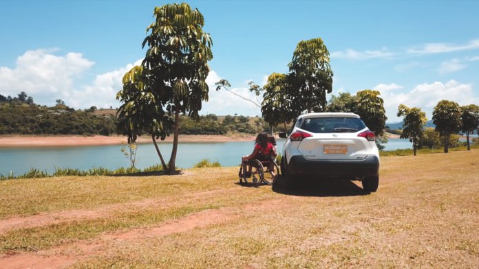 Descrição da imagem #PraTodosVerem: Imagem no formato retangular, na horizontal. Mãe e filha ao lado do Nissan Kicks. Elas estão em um parque, à beira de uma represa. Fim da descrição;