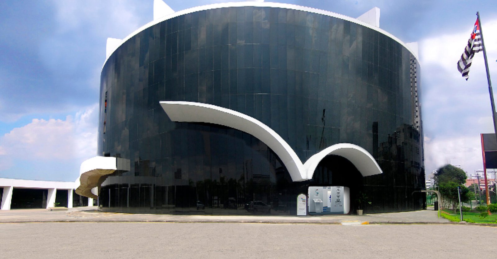 Descrição da imagem #PraCegoVer: Imagem no formato retangular, na horizontal. Fachada do prédio do Memorial da Inclusão. O prédio tem formato circular, e é pintado de preto, com detalhes na cor branca. Fim da descrição.