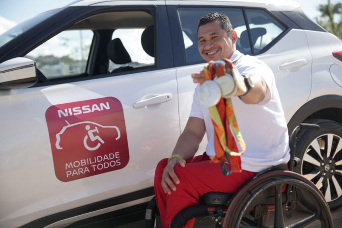 Descrição da imagem #PraCegoVer: Imagem no formato retangular, na horizontal. O paratleta Clodoaldo Silva, posa com suas medalhas. Ele está ao lado de um Nissan Kicks branco. Na porta do carro está um adesivo escrito 