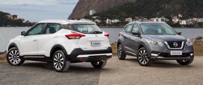Descrição da imagem #PraCegoVer: Imagem em formato retangular, na horizontal. Nela estão dois modelos de automóveis da marca Nissan: O Kicks e o March. Ao fundo vemos o mar. Fim da descrição.