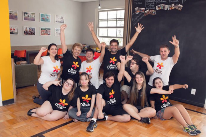 Descrição da imagem #PraCegoVer: Imagem no formato retangular, na horizontal. A equipe do Instituto Mano Down. Eles estão na sede do Instituto e usam a camiseta do Instituto Mano Down. Fim da descrição.