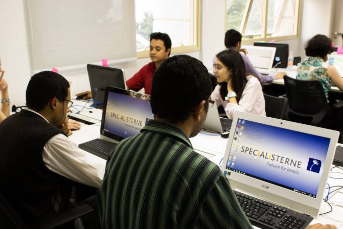 Descrição da imagem #PraCegoVer: Imagem no formato retangular, na horizontal. Um grupo de jovens está trabalhando em um escritório. Eles estão sentados em frente a computadores. Fim da descrição.