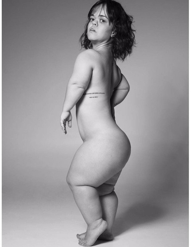 Descrição da imagem #PraCegoVer: Imagem no formato retangular, na horizontal. Imagem em preto e branco da atriz Juliana Caldas em ensaio nu para o Pele Project. Juliana está nua e está olhando de lado. É possível ver sua tatuagem na costela. Fim da descrição.