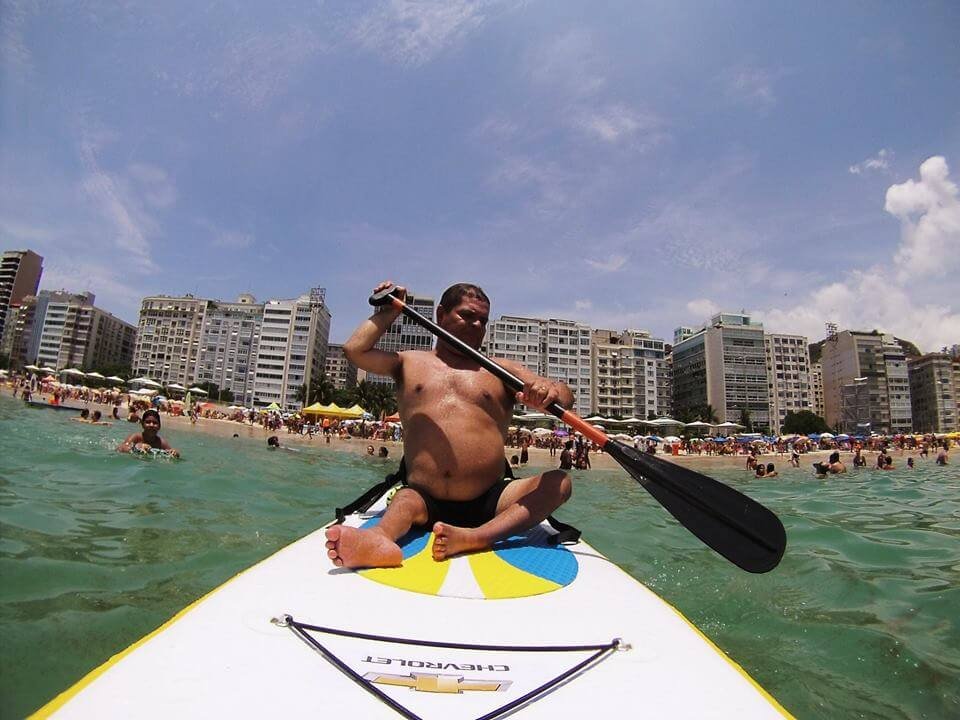 Descrição da imagem #PraCegoVer: Imagem no formato retangular, na horizontal. Um grupo de pessoas jogando vôlei sentado, na praia. Fim da descrição.