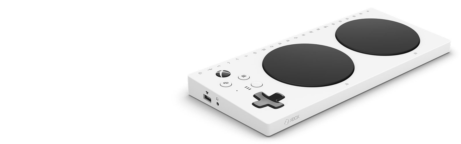Descrição da imagem #PraCegoVer: Imagem no formato retangular, na horizontal. O Xbox Adaptive Controller, da Microsoft. Ele tem formato retangular, é todo branco, e tem dois grandes botões pretos, em forma de círculo, alguns botões menores, brancos, e um botão preto em formato de cruz. Fim da descrição.