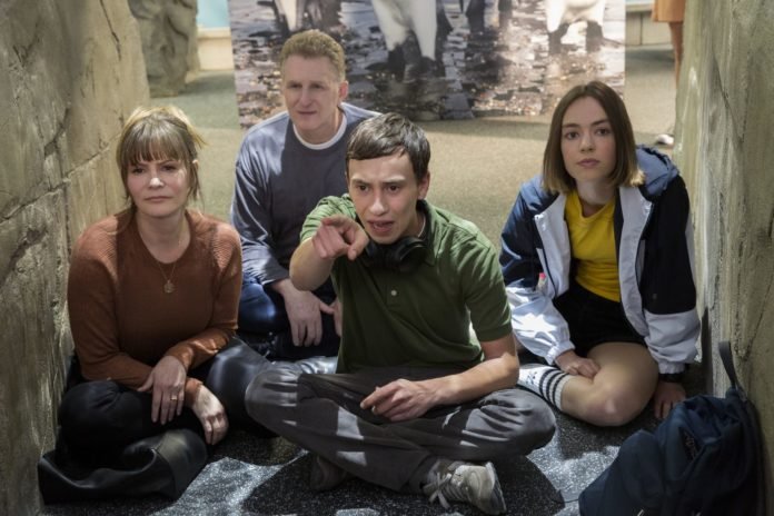 Descrição da imagem: Foto de divulgação da série Atypical. Os personagens estão no aquário. Eles estão sentados no chão e observam um aquário. Fim da descrição.