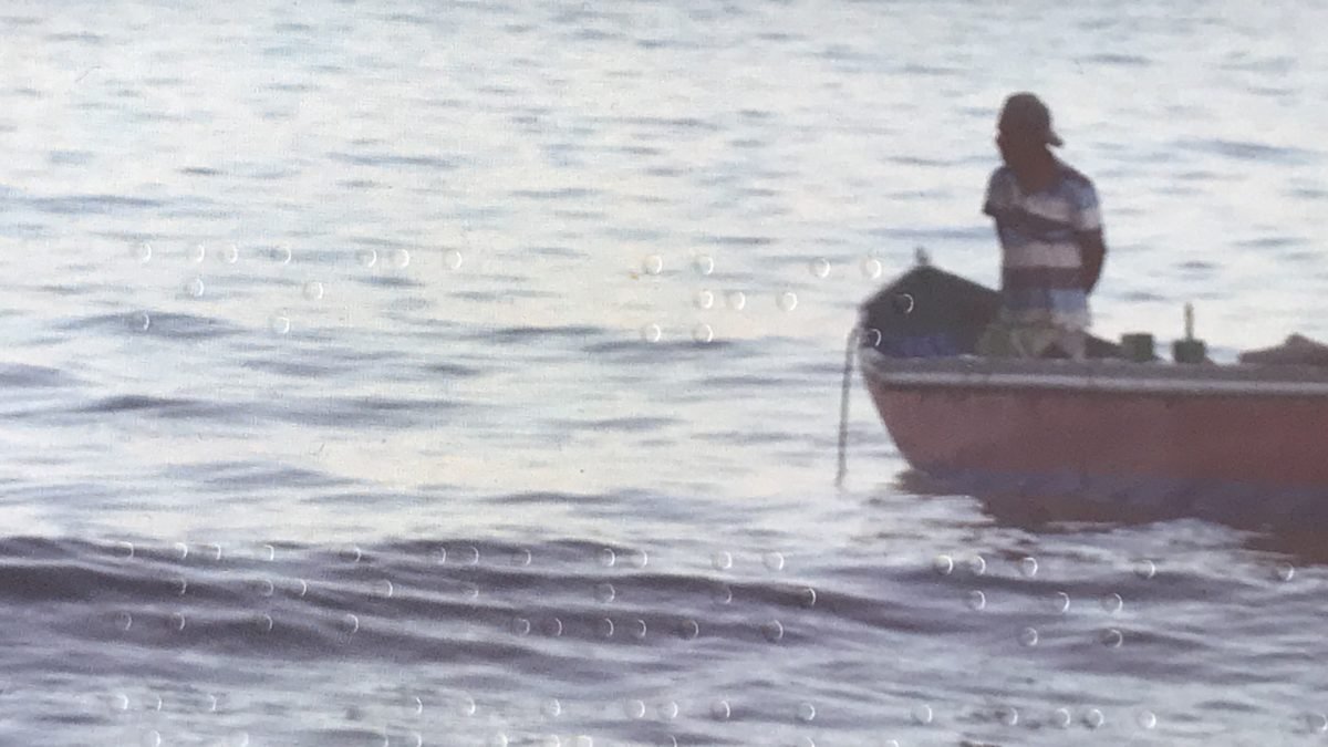 Descrição da imagem #PraCegoVer: Imagem no formato retangular, na horizontal. Detalhe do braile na capa da revista com acessibilidade para cegos da ESPM-Rio. A imagem é de uma praia, onde vemos um barco se aproximando da faixa de areia. A imagem tem tons acinzentados. Fim da descrição.