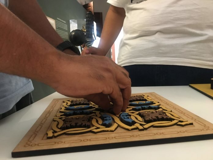 Descrição da imagem #PraCegoVer: Imagem no formato retangular, na horizontal. Close das mãos do jornalista Ismael da Silva, que está tateando peças que compõem a mostra tátil do Museu da Energia de São Paulo. A peça que ele está tateando representa um dos desenhos do piso do museu. Fim da descrição.