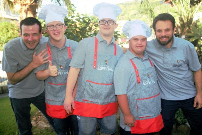 Descrição da imagem #PraCegoVer: Imagem no formato retangular, na horizontal. A equipe da Cafeteria Especial, que é formada por profissionais com síndrome de Down. Eles estão uniformizados e sorrindo. Fim da descrição.