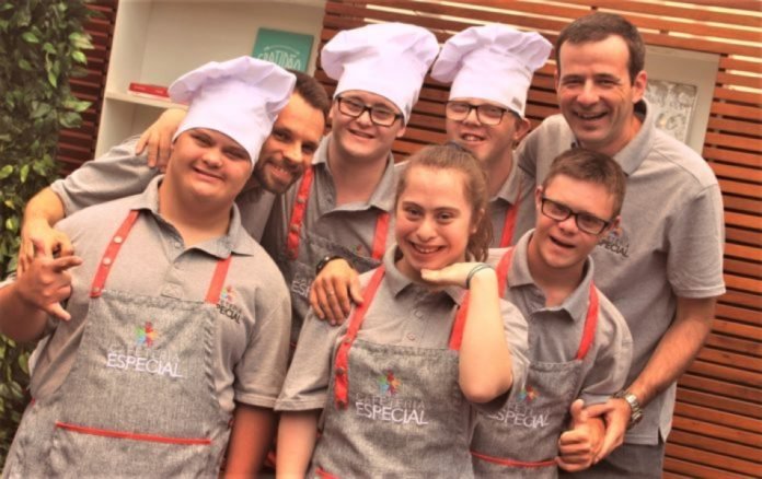 Descrição da imagem #pracegover: Foto da equipe da Cafeteria Especial, que é formada por profissionais com síndrome de Down. Eles estão uniformizados e sorrindo. Fim da descrição.