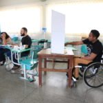 Descrição da imagem #PraCegoVer: Imagem no formato retangular, na horizontal. Pessoas com deficiência durante a votação em uma sessão eleitoral acessível. Fim da descrição.