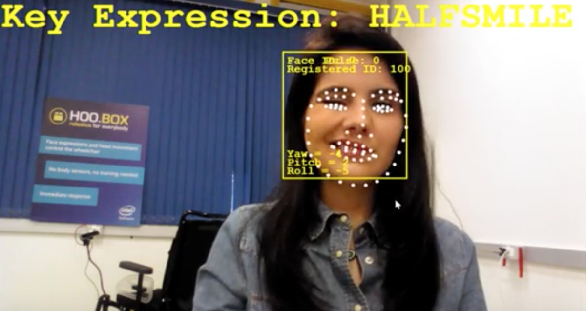 Descrição da imagem #PraCegoVer: Imagem no formato retangular, na horizontal. Uma mulher está em frente a uma câmera. Seu rosto está coberto por pontos digitais que mostram o funcionamento do sistema de comando por movimentos da face. Ela é morena e tem pele clara e cabelos pretos, lisos e compridos. Fim da descrição.