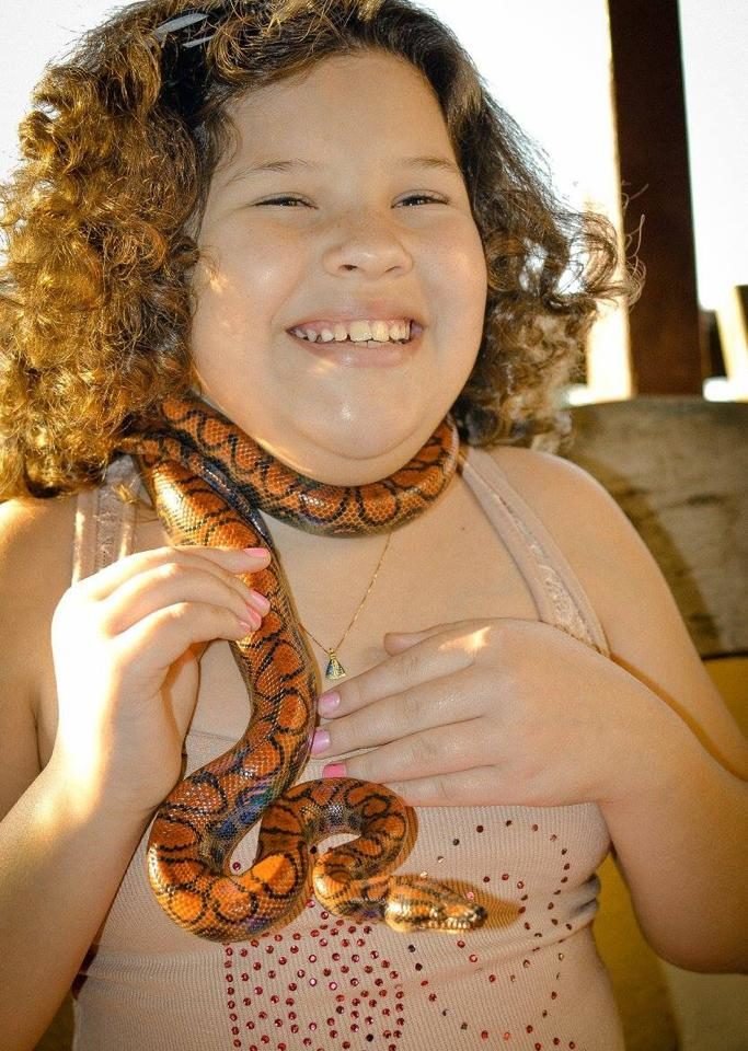 Descrição da imagem #pracegover: Uma menina está com uma cobra. Fim da descrição.