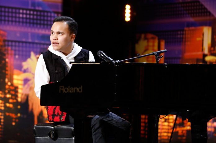 Descrição da imagem #PraCegoVer: Imagem no formato retangular, na horizontal. Kodi Lee durante apresentação no America's Got Talent. Ele está no palco, sentado à frente do piano. Kodi é um rapaz moreno, de pele clara e cabelos pretos, curtos. Ele usa uma camisa branca, calça e colete preto. Fim da descrição.