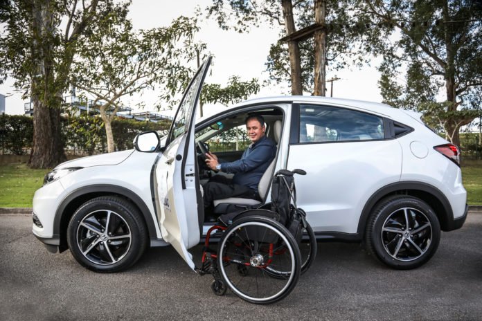 Descrição da imagem #PraCegoVer: Robson Jeronimo está sentado no banco do motorista do modelo Honda HR-V. A porta está aberta e sua cadeira de rodas está ao lado da porta. Fim da descrição.