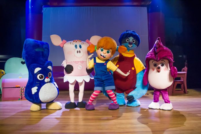 Descrição da imagem #PraCegoVer: Cena do musical O Diário de Mika. Os cinco personagens da peça estão no centro do palco. Eles são Puquê, um gatinho azul; Lilá, uma porquinha travesseiro cor de rosa; Mika, uma menina de roupas coloridas e cabelos vermelhos; Javô, uma espreguiçadeira em forma de bicho-preguiça azul; e Bru, um ouriço de pelúcia lilás. Fim da descrição.