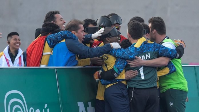 Descrição da imagem #PraCegoVer: Os jogadores de futebol de 5 estão abraçados, comemorando um gol na final. Fim da descrição.