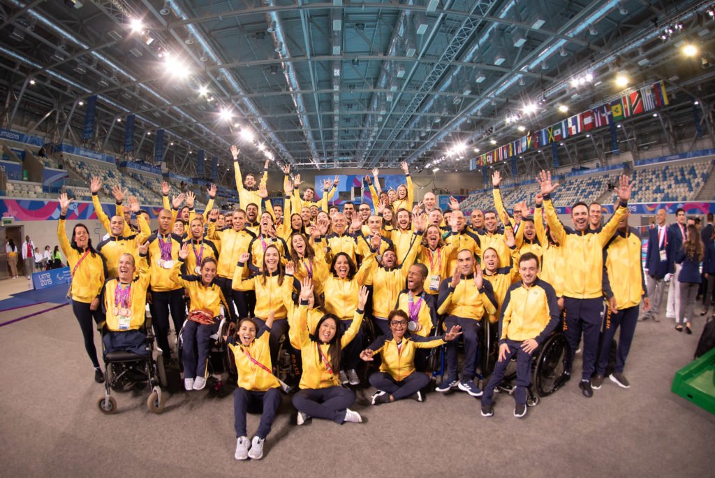 Descrição da imagem #PraCegoVer: Vários atletas da delegação brasileira de natação estão no parque aquático de Lima. Eles usam uniforme amarelo e azul marinho. Fim da descrição.