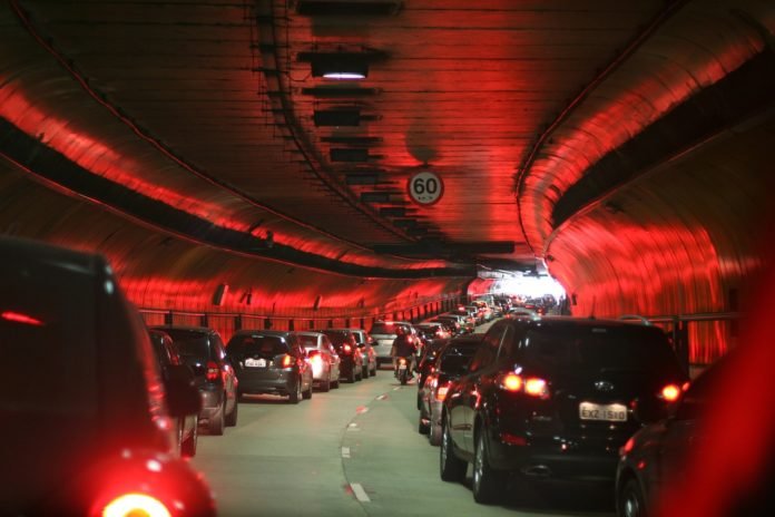 Descrição da imagem #PraCegoVer: Duas fileiras de carros dentro de um túnel da cidade de São Paulo. Podemos dizer que se trata de um congestionado na hora do rush paulistano. Reflexos de luzes vermelhas são vistos nas paredes escuras do túnel. Fim da descrição.