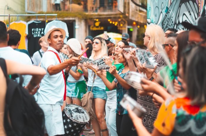 Descrição da imagem #PraCegoVer: Várias pessoas estão se divertindo em um bloco de Carnaval de rua. Fim da descrição.