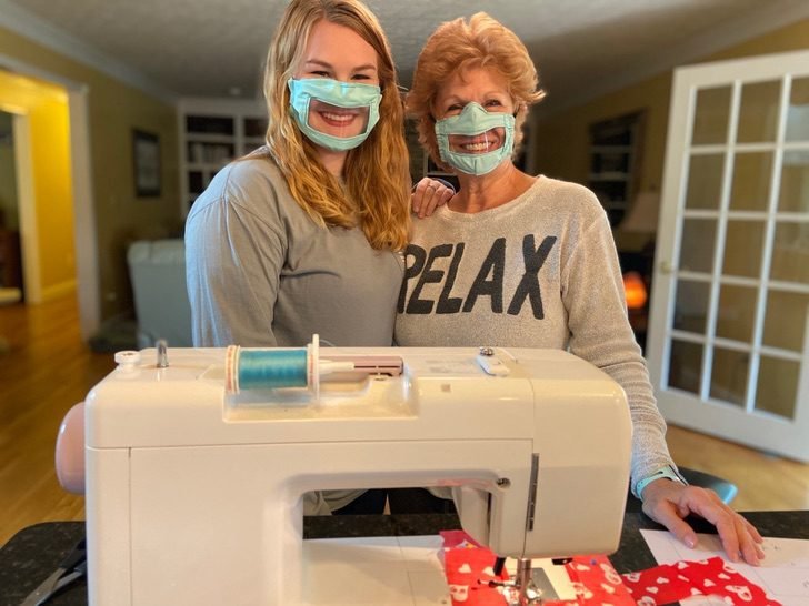 Descrição da imagem #PraCegoVer: A estudante Ashley e sua mãe estão abraçadas. Elas usam a máscara adaptada, que é azul clara e tem uma abertura transparente na parte da boca. Fim da descrição.