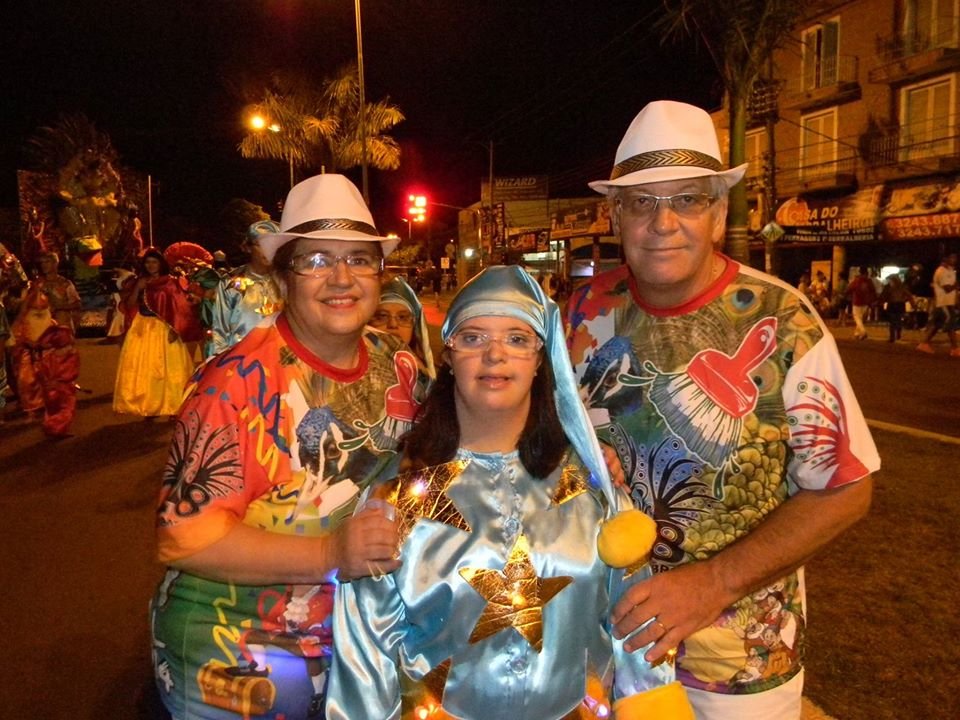Descrição da imagem #pracegover: Foto de Tomás André com a filha e a esposa durante evento de Carnaval. O casal está usando camisetas coloridas e a menina está usando uma fantasia. Fim da descrição.