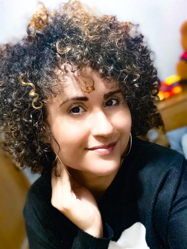 Descrição da imagem #pratodosverem: Ana Cristina. Ela é morena e tem os cabelos cacheados. Fim da descrição.