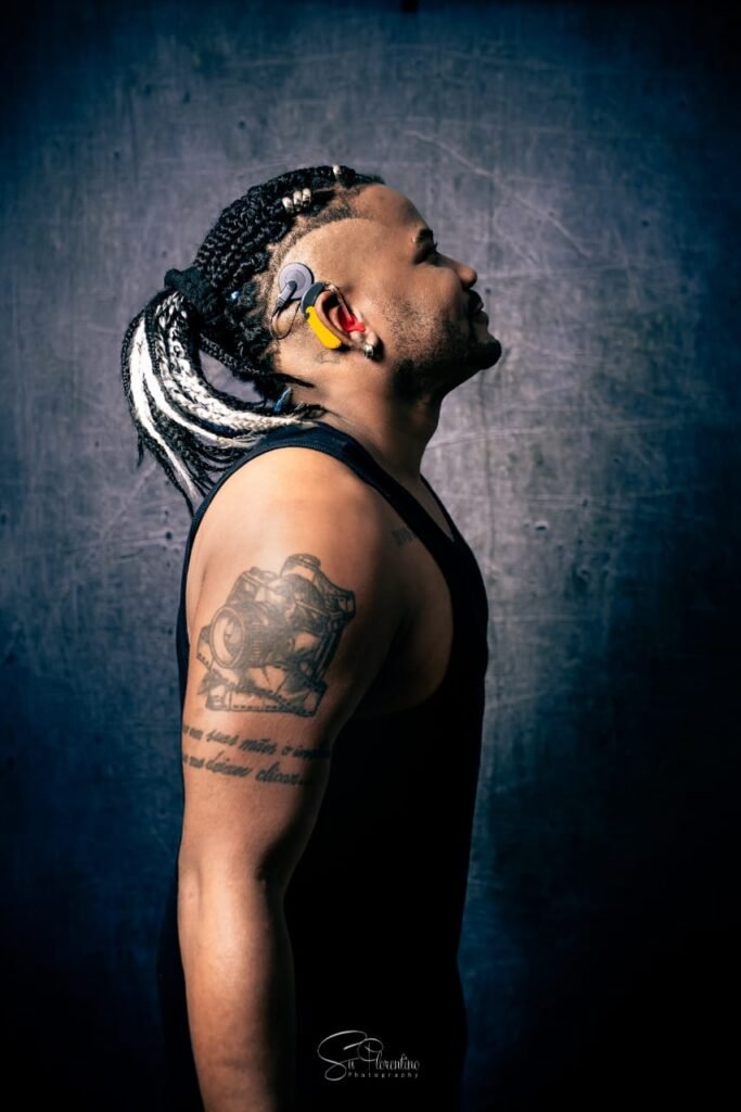 Descrição da imagem #pracegover: Foto de perfil do coreógrafo surdo Jhonny. Ele é um homem negro e tem cabelos longos, trançados. Jhonny usa uma regata preta e tem os braços tatuados. Fim da descrição.