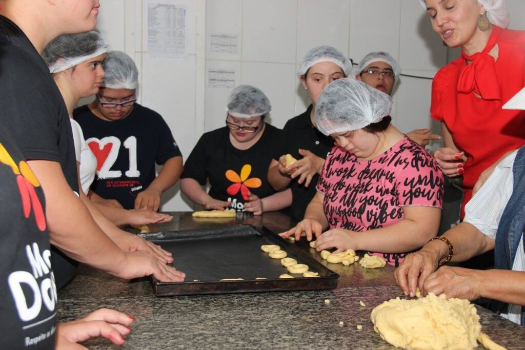 Descrição da imagem #pracegover: Os atendidos pelo Instituto Mano Down durante uma aula de culinária. Fim da descrição.