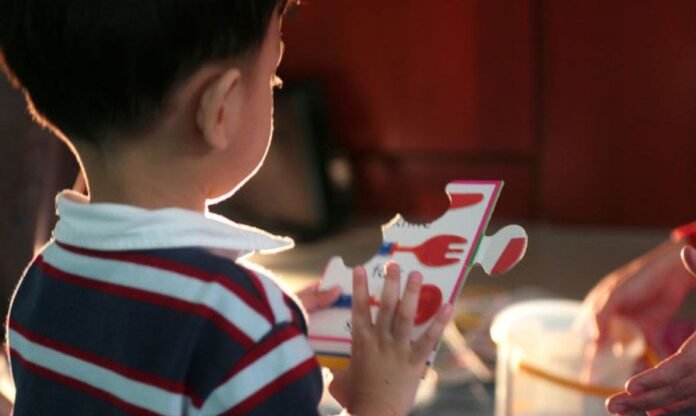 Descrição da imagem #pratodosverem: Um menino está brincando com uma peça de brinquedo. Ele está de costas. Fim da descrição. Descrição da imagem #pratodosverem: Um menino está brincando com uma peça de brinquedo. Ele está de costas. Fim da descrição.