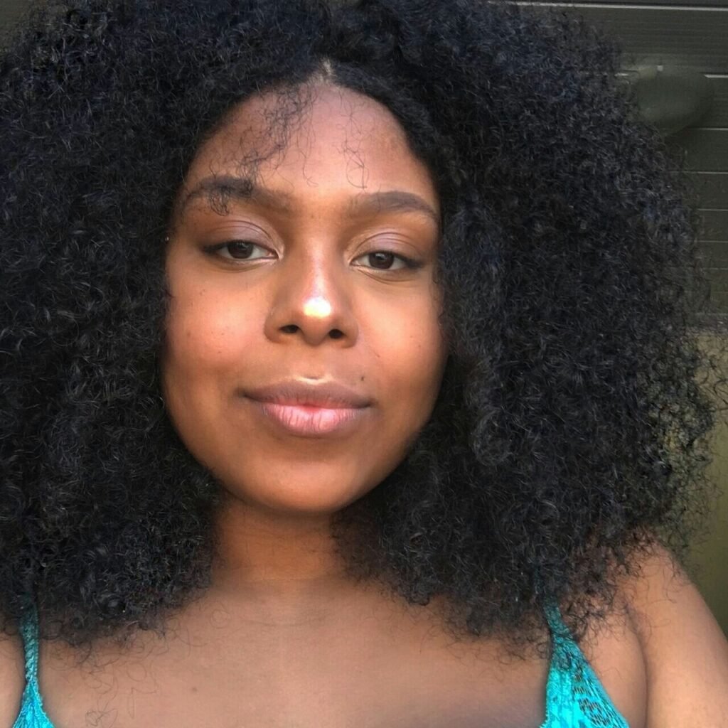 Descrição da imagem #pracegover: Close da Lele, blogueira pcd. Ela é uma mulher preta e linda. Lele tem cabelos pretos, cacheados, na altura dos ombros. Ela usa uma blusa de alcinha azul. Fim da descrição.