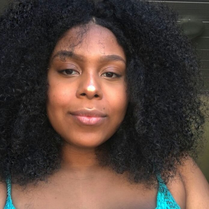 Descrição da imagem #pracegover: Close da Lele, blogueira pcd. Ela é uma mulher preta e linda. Lele tem cabelos pretos, cacheados, na altura dos ombros. Ela usa uma blusa de alcinha azul. Fim da descrição.